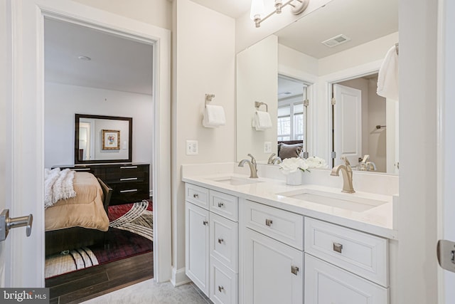 full bath featuring double vanity, visible vents, a sink, and connected bathroom