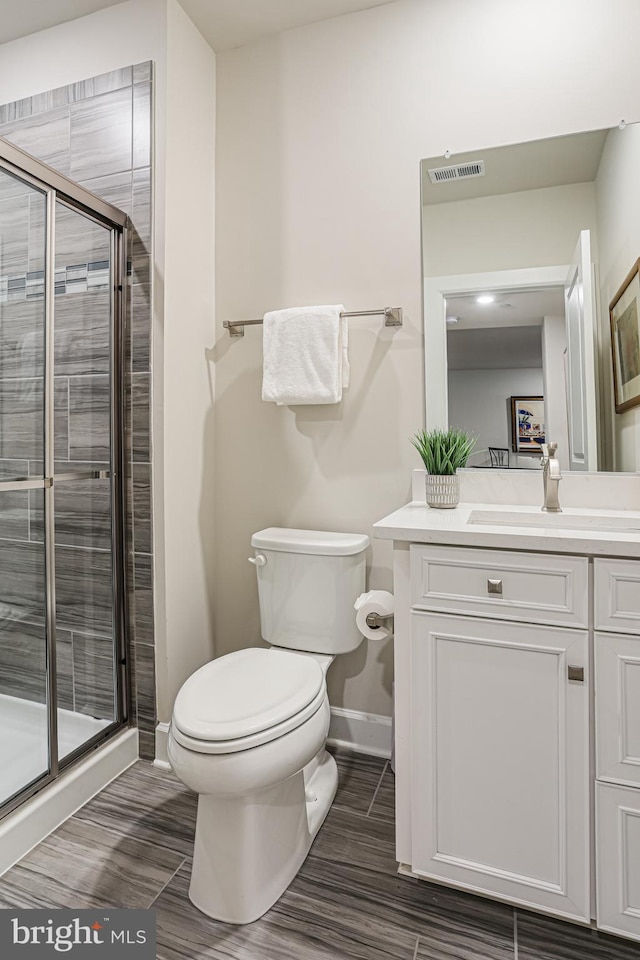 full bath with a shower stall, toilet, vanity, baseboards, and visible vents