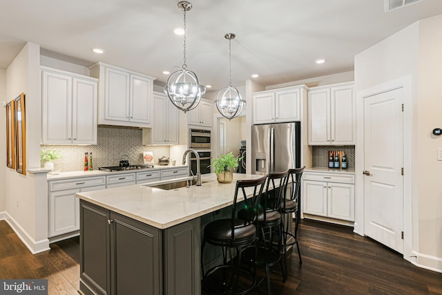 kitchen featuring a sink, dark wood finished floors, backsplash, white cabinetry, and appliances with stainless steel finishes