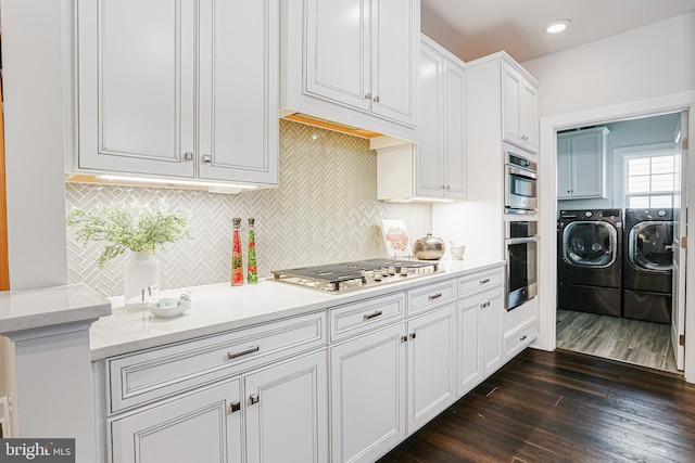 kitchen with white cabinets, dark wood-style flooring, decorative backsplash, washer and dryer, and appliances with stainless steel finishes