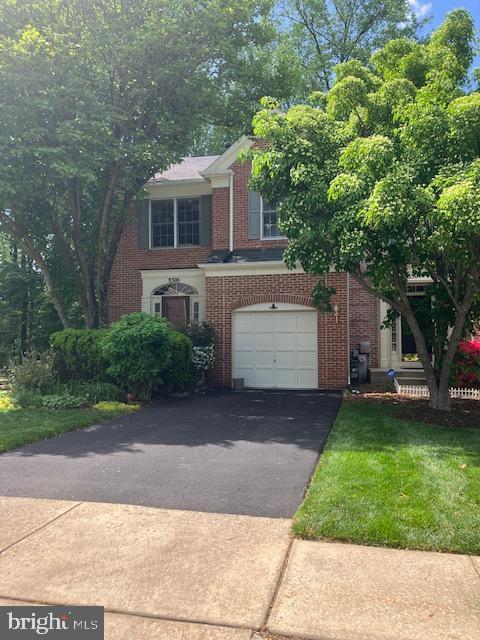 view of front of house with brick siding, a front lawn, an attached garage, and driveway
