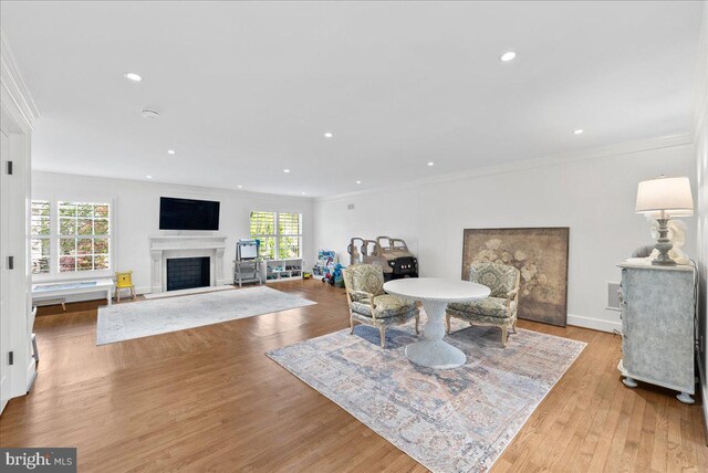 dining room featuring crown molding, light wood-style floors, and a fireplace