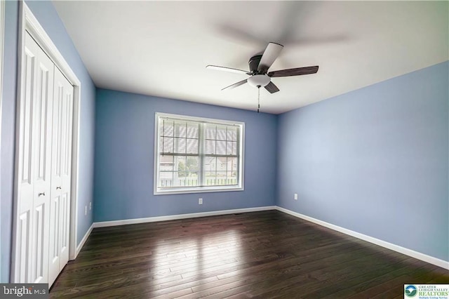 unfurnished bedroom with dark wood-type flooring, a closet, and baseboards