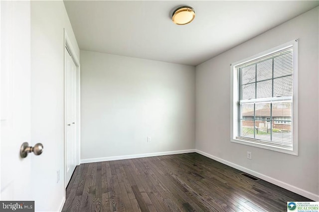 unfurnished bedroom featuring a closet, visible vents, dark wood-style flooring, and baseboards