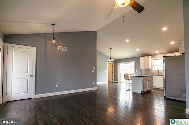 unfurnished living room featuring ceiling fan with notable chandelier, visible vents, a sink, and vaulted ceiling