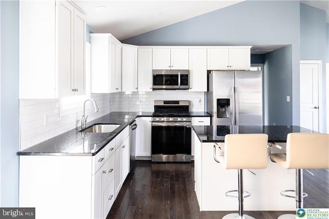 kitchen featuring a sink, a kitchen bar, white cabinetry, stainless steel appliances, and lofted ceiling