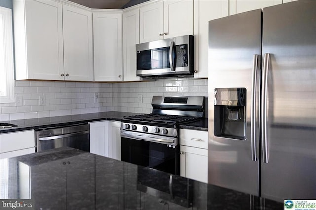 kitchen with white cabinetry, decorative backsplash, appliances with stainless steel finishes, and dark stone countertops