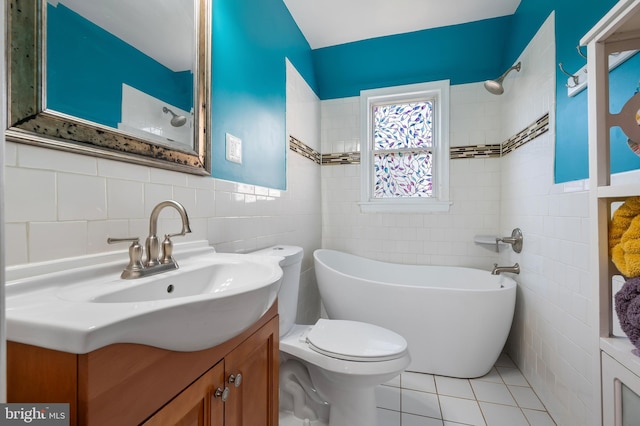 bathroom featuring a tub to relax in, tile patterned floors, toilet, vanity, and tile walls