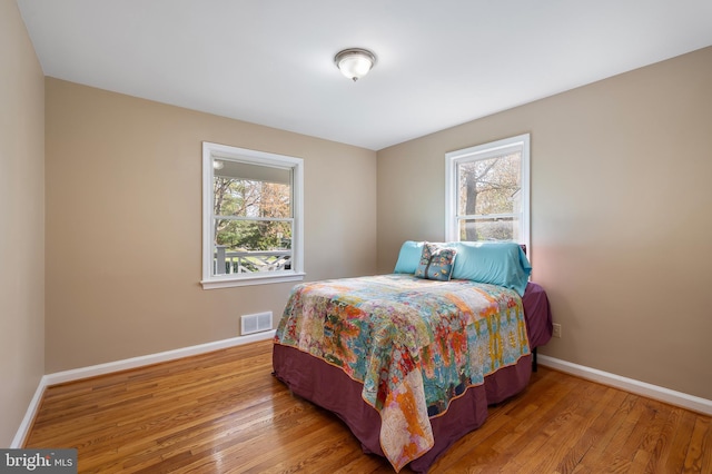 bedroom with light wood-style floors, visible vents, and baseboards