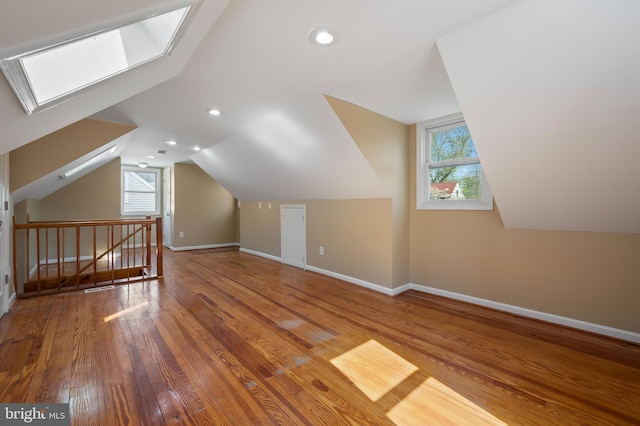 bonus room featuring baseboards, vaulted ceiling with skylight, wood finished floors, and recessed lighting