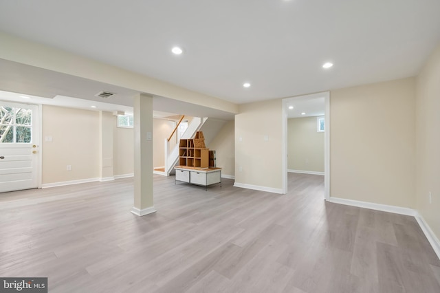 basement featuring baseboards, visible vents, light wood-style floors, and stairway