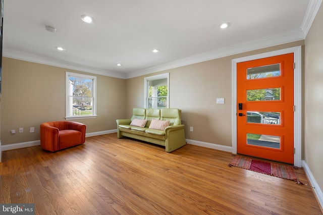 living area featuring light wood-style flooring, baseboards, and crown molding