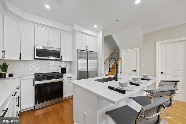kitchen with light wood-type flooring, a sink, white cabinetry, and appliances with stainless steel finishes