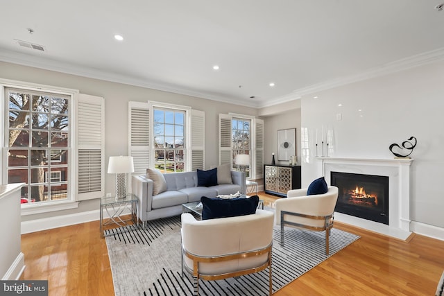 living room with a fireplace with flush hearth, light wood-style floors, baseboards, and ornamental molding