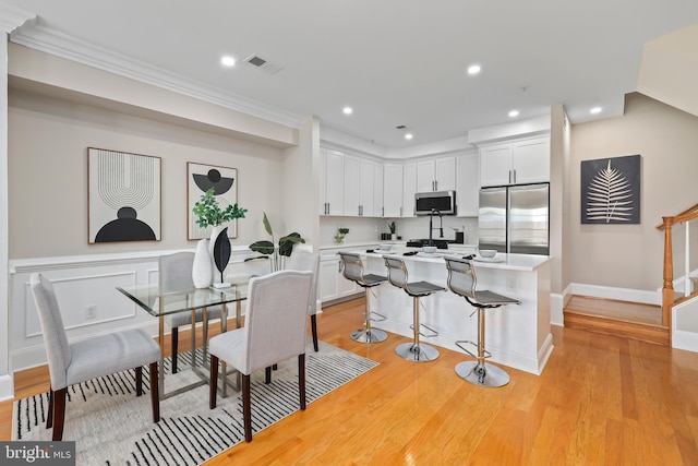 dining room featuring recessed lighting, light wood finished floors, visible vents, crown molding, and baseboards
