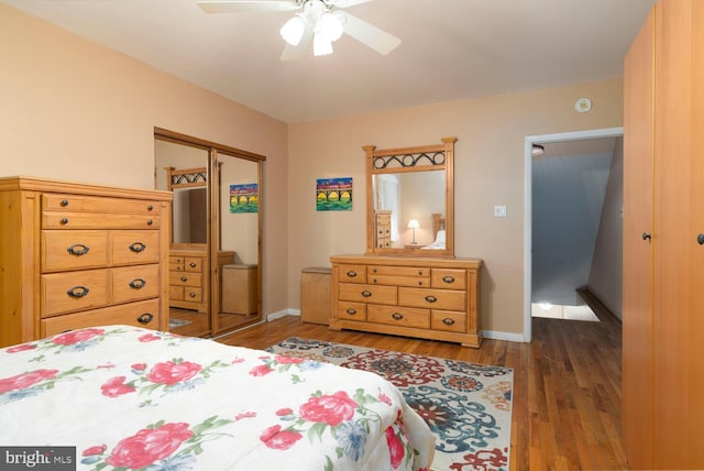 bedroom with baseboards, ceiling fan, wood finished floors, and a closet