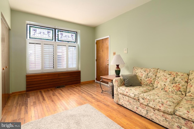 living room featuring baseboards, visible vents, and hardwood / wood-style flooring