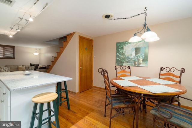 dining space with baseboards, light wood finished floors, stairs, and visible vents