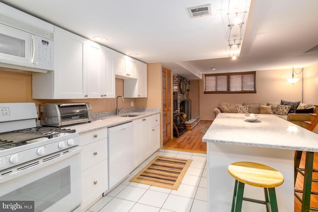 kitchen with a wood stove, a toaster, white appliances, open floor plan, and a sink