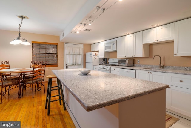 kitchen with a center island, a sink, light wood-style floors, white appliances, and white cabinetry