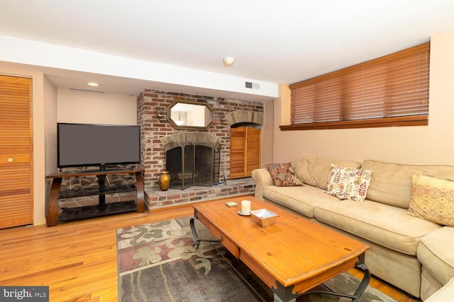 living room with recessed lighting, visible vents, wood finished floors, and a fireplace