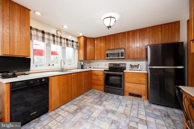 kitchen featuring brown cabinets, a toaster, light countertops, a sink, and black appliances