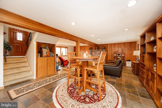dining room featuring wood walls, stone tile flooring, recessed lighting, and stairway