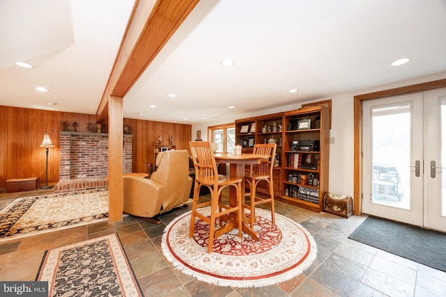 dining room with recessed lighting, stone tile flooring, wood walls, and french doors