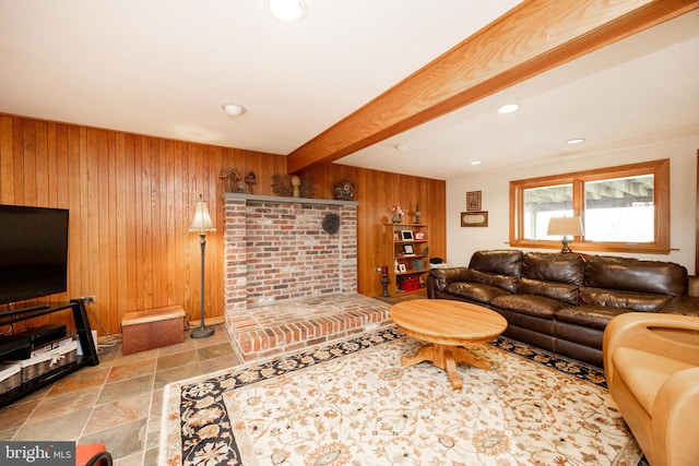 living room with beam ceiling, recessed lighting, a brick fireplace, stone finish flooring, and wooden walls
