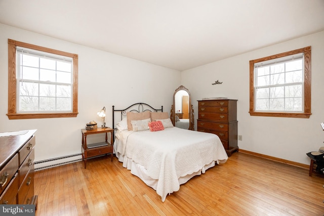 bedroom featuring baseboard heating, baseboards, multiple windows, and light wood-type flooring