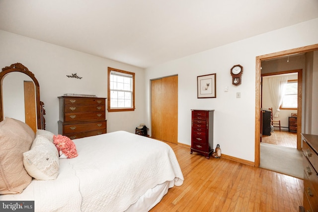 bedroom with baseboards, a closet, and light wood-type flooring