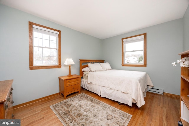 bedroom featuring a baseboard radiator, light wood-type flooring, and multiple windows