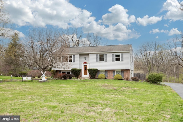 raised ranch featuring brick siding and a front yard