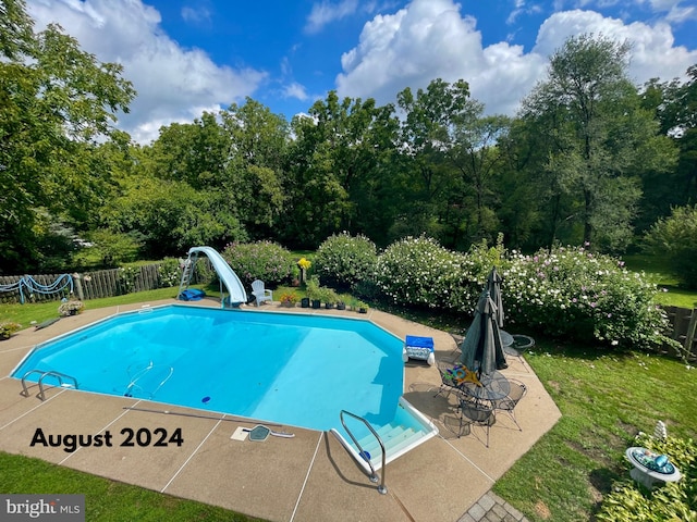 view of swimming pool featuring a patio area, a water slide, a fenced in pool, and fence