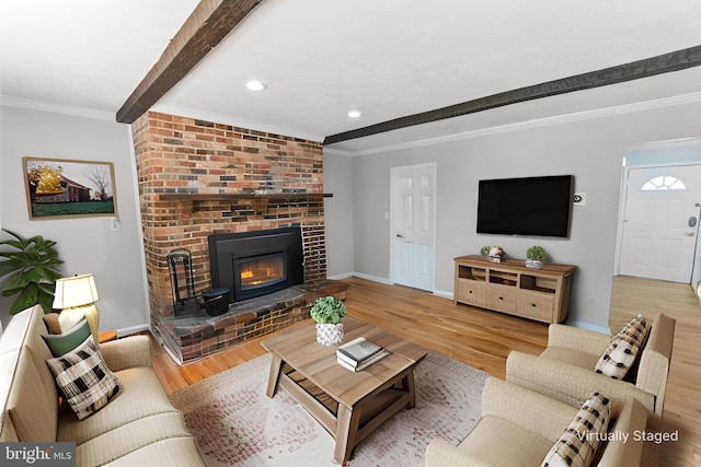 living area featuring baseboards, wood finished floors, a fireplace, and beamed ceiling