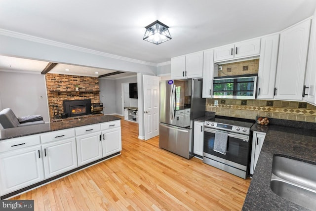 kitchen featuring appliances with stainless steel finishes, white cabinetry, light wood-style flooring, and open floor plan