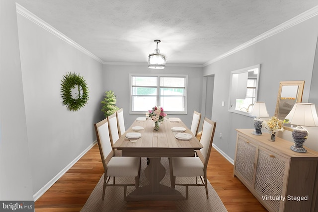 dining space featuring crown molding, baseboards, and wood finished floors
