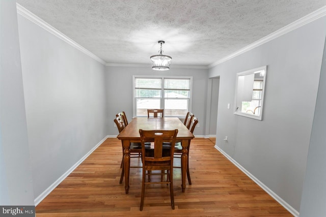 dining space with baseboards, an inviting chandelier, ornamental molding, and light wood-type flooring