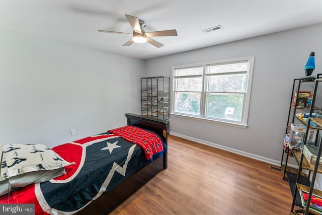 bedroom with baseboards, ceiling fan, wood finished floors, and visible vents