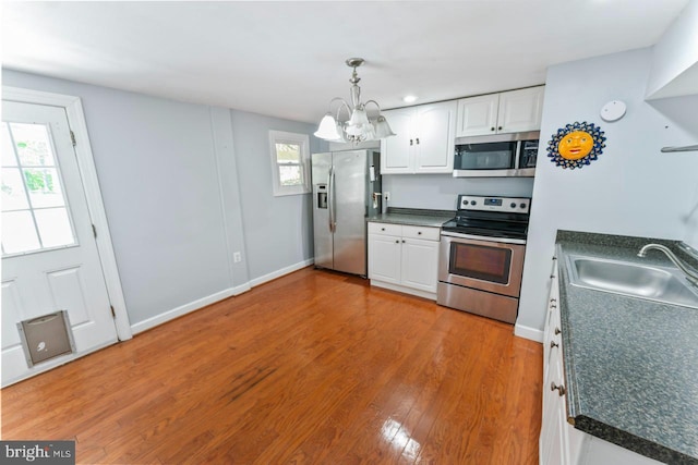 kitchen featuring an inviting chandelier, white cabinets, a sink, appliances with stainless steel finishes, and a wealth of natural light