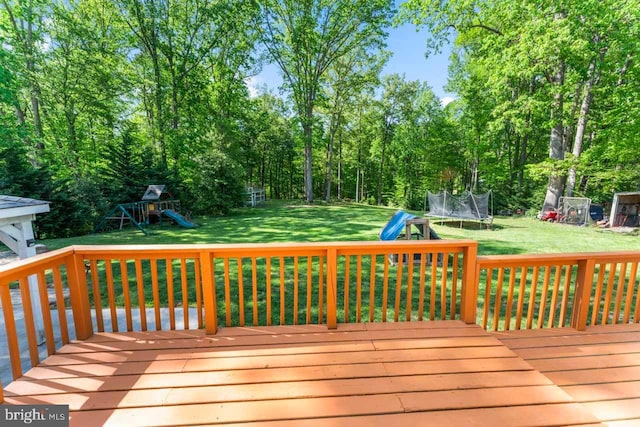 wooden deck featuring a trampoline, a playground, and a yard