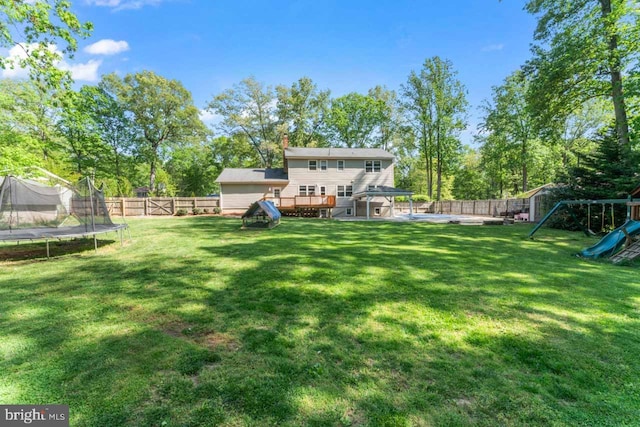 view of yard with a playground, a trampoline, a fenced backyard, and a deck