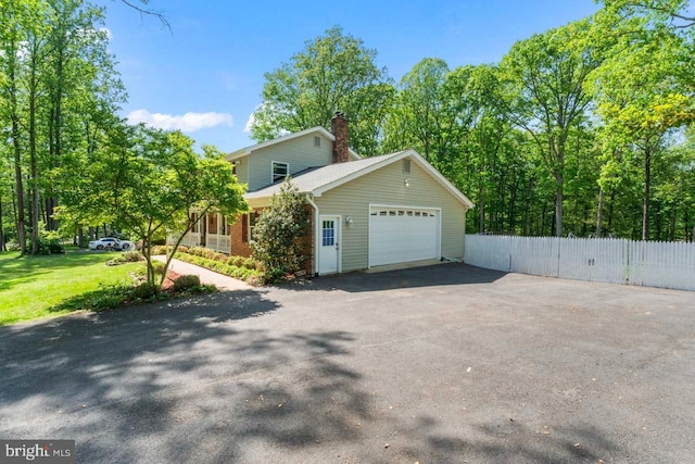view of side of property featuring fence, an attached garage, brick siding, aphalt driveway, and a chimney