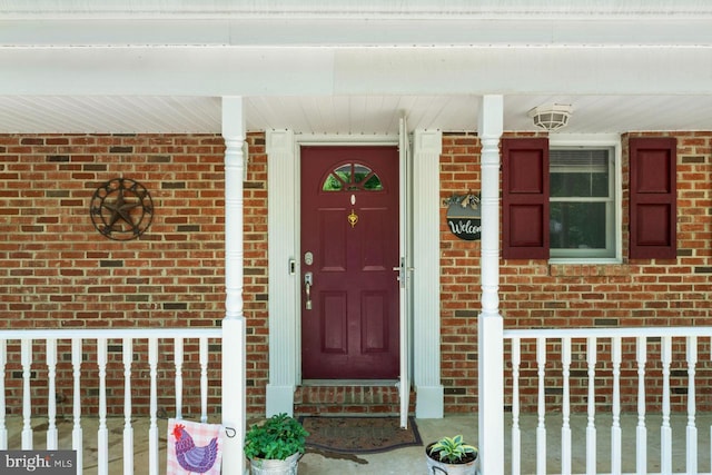 entrance to property with brick siding and a porch