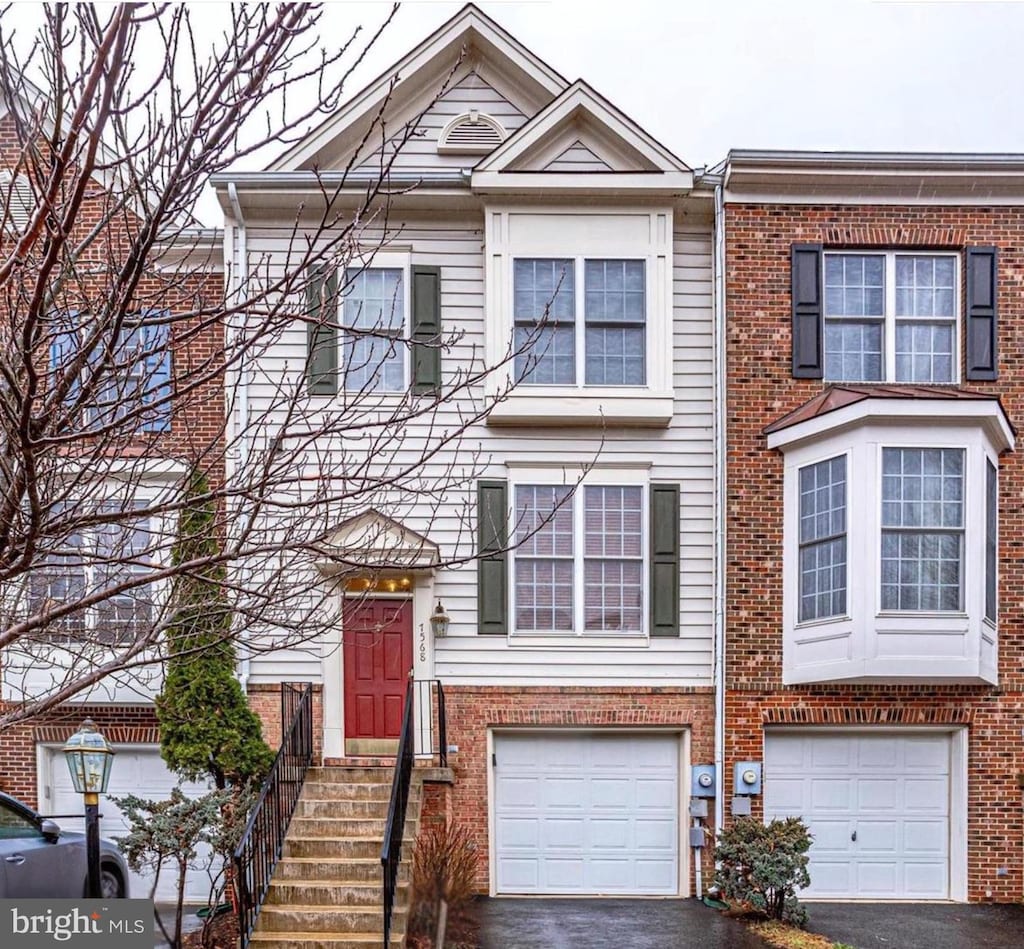 townhome / multi-family property with brick siding, driveway, and a garage