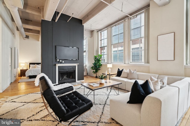 living room with a fireplace with flush hearth, wood finished floors, and beamed ceiling