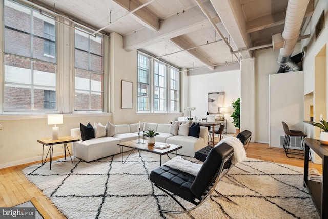 living room featuring beamed ceiling, baseboards, and hardwood / wood-style floors