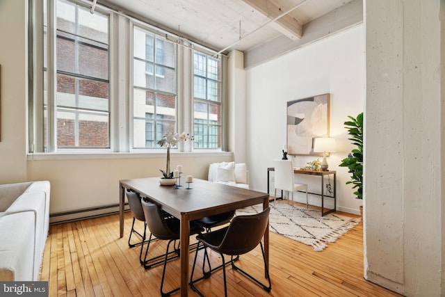 dining space with light wood-style flooring, a baseboard radiator, and beam ceiling