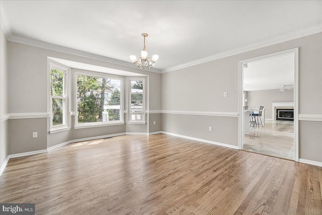 5342 Saint James Pl, Frederick, MD 21703 - unfurnished dining area with an inviting chandelier, a glass covered fireplace, crown molding, baseboards, and wood finished floors