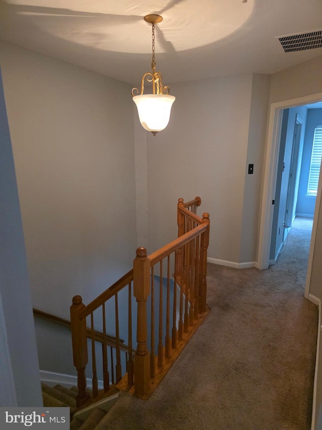 interior space featuring baseboards, visible vents, carpet floors, and an upstairs landing